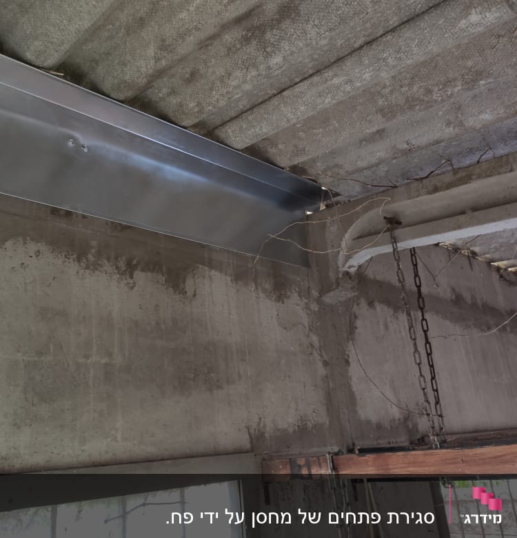 קורת מתכת מותקנת על קיר בטון במהלך שיפוץ